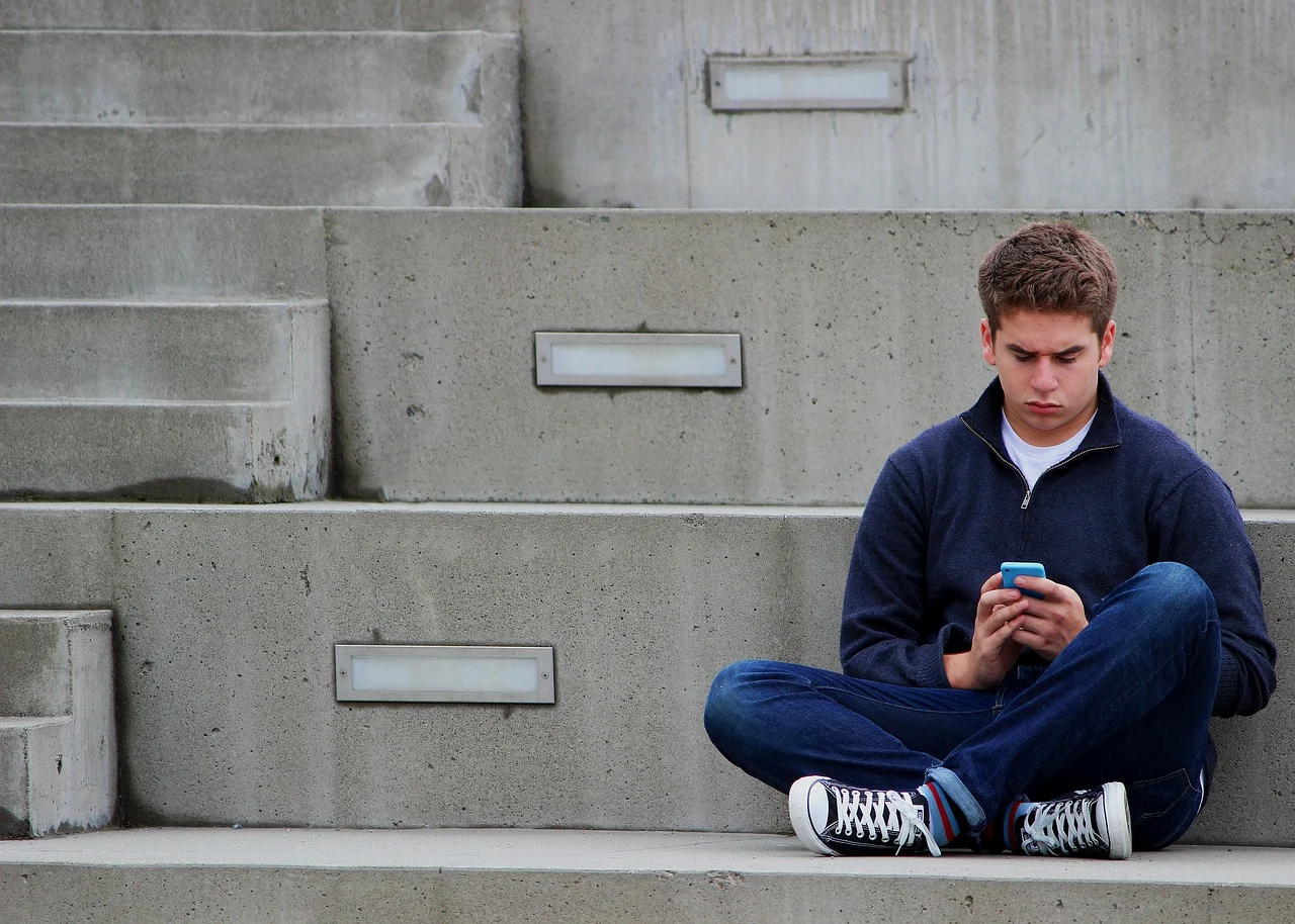 Adolescent utilisant un téléphone portable pour envoyer un message