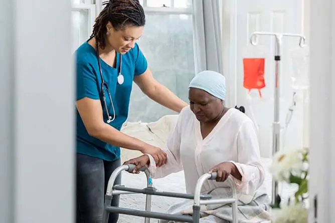 臨終關懷護士幫助一位年長的婦女起床。